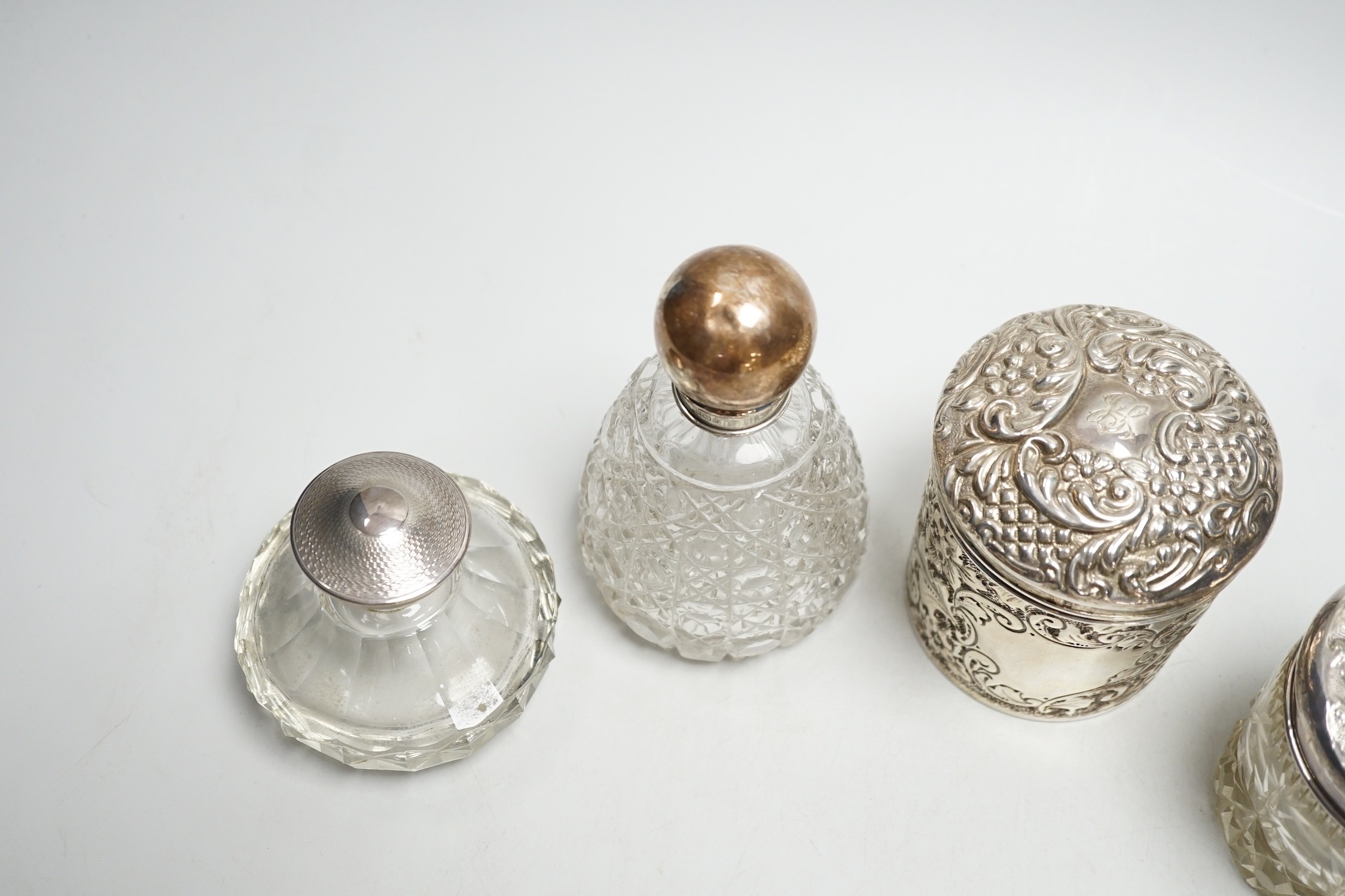 Two repousse silver lidded toilet jars, including glass, largest, 95mm and two silver mounted glass scent bottles.